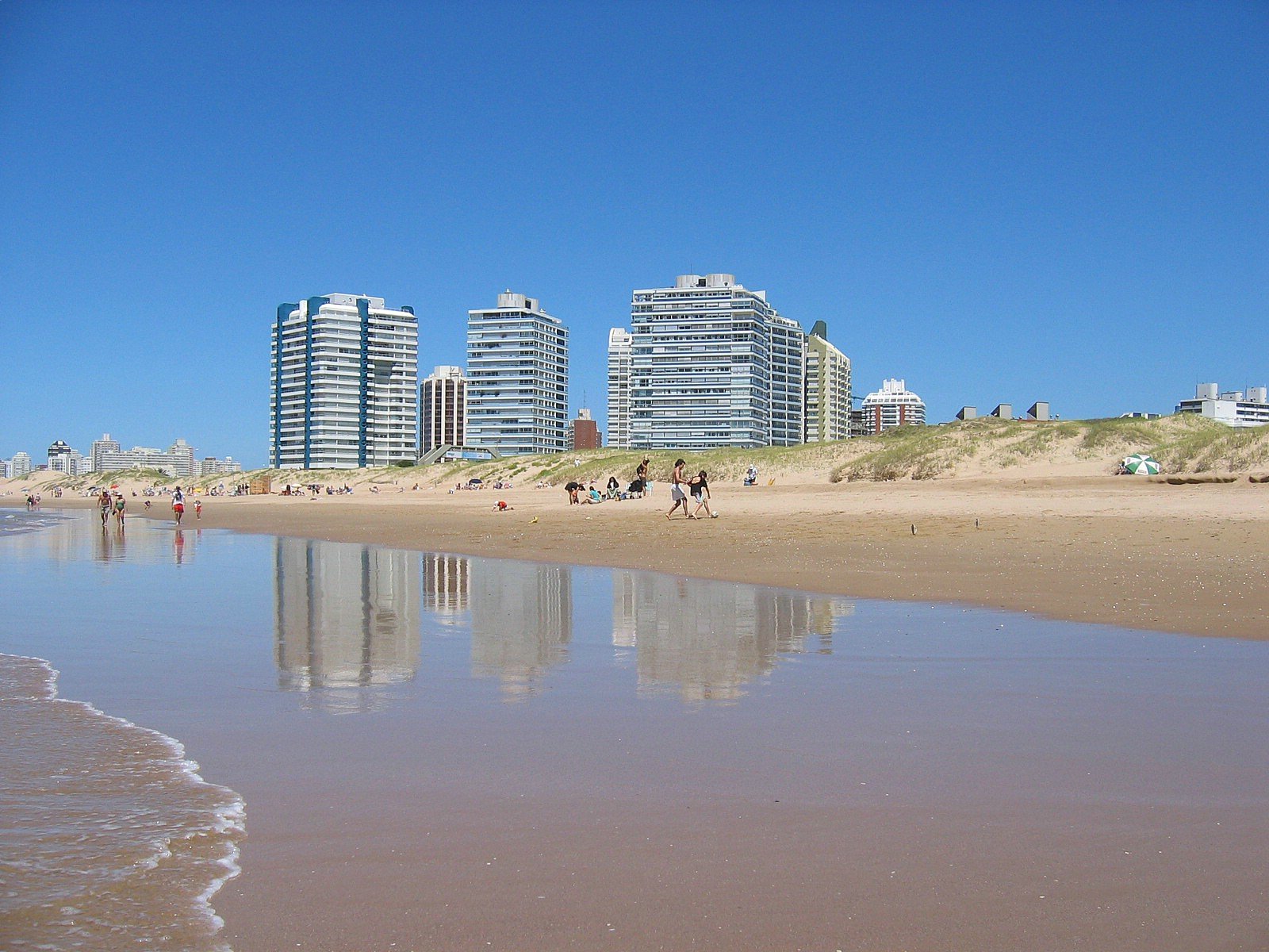 a beach with lots of people walking in the sand