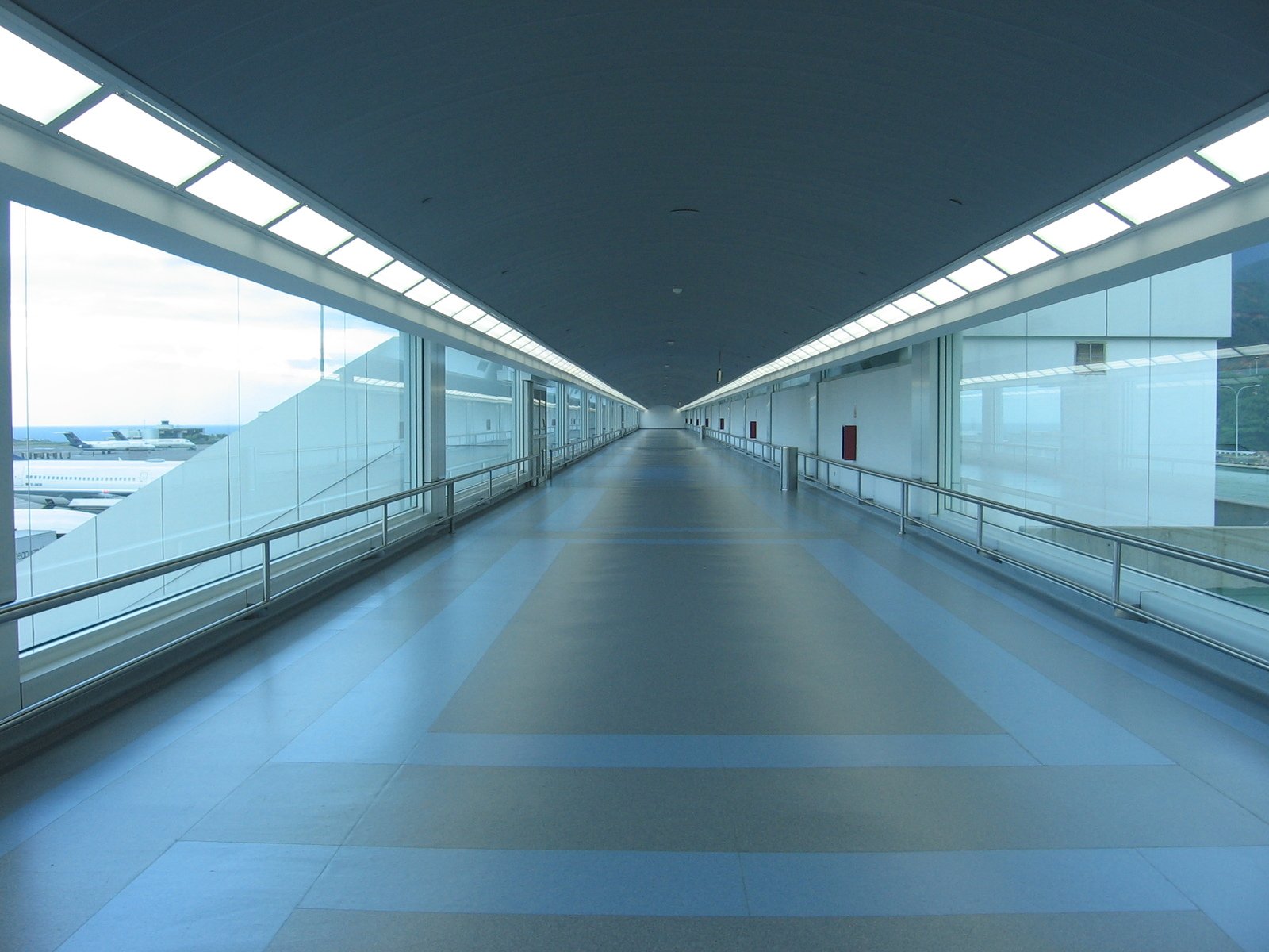 a walkway way through a terminal near a fence