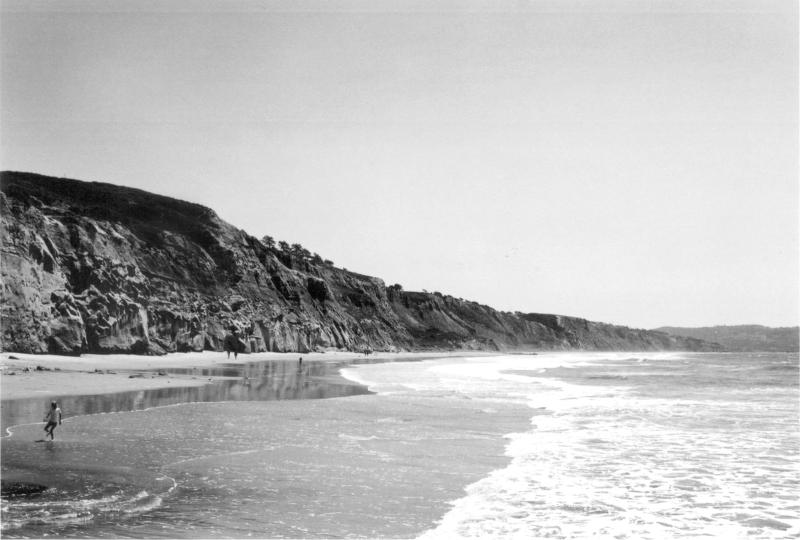 a person is walking in shallow water along the beach