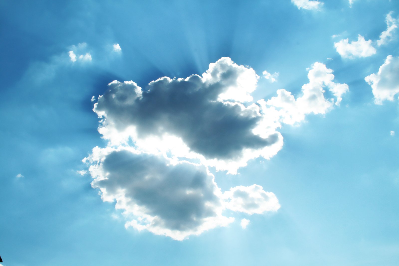 a view up into the blue sky and clouds with bright sunshine coming through them