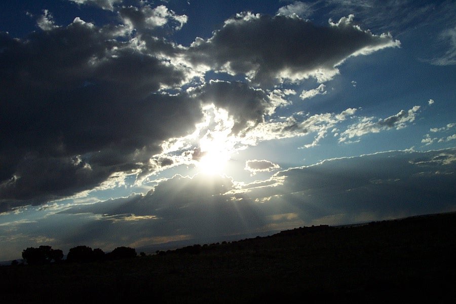 the sun through the clouds over some trees