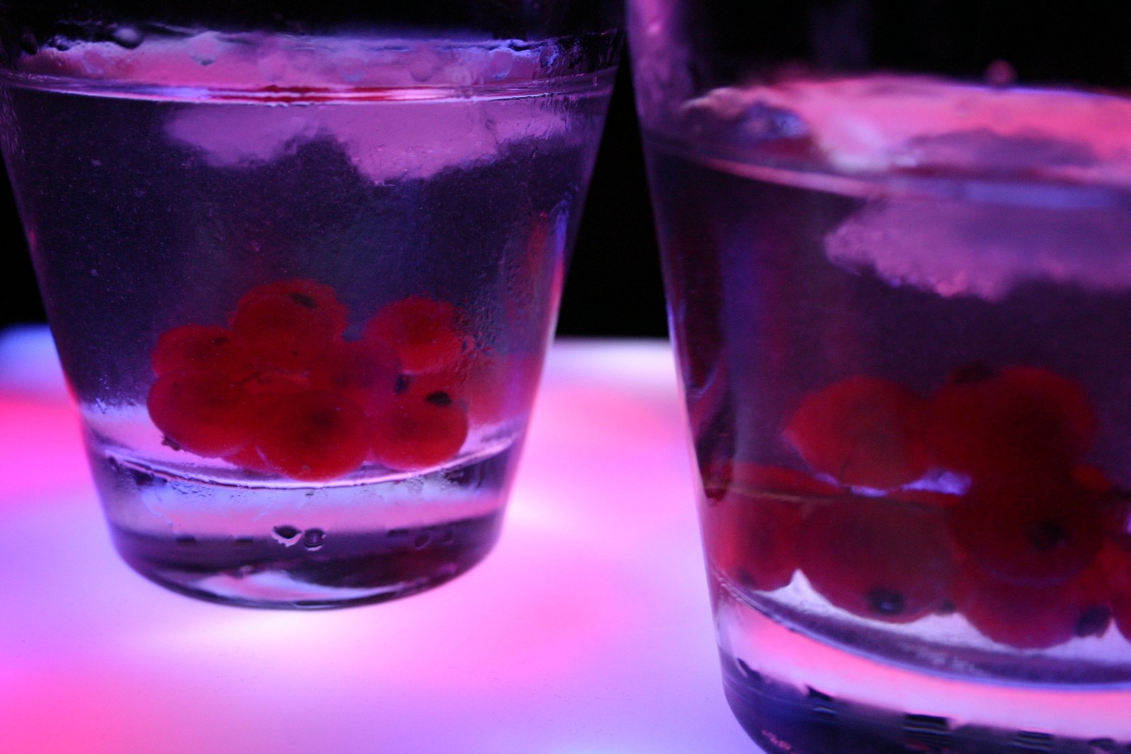 three different cups of liquid with red cherries on the top