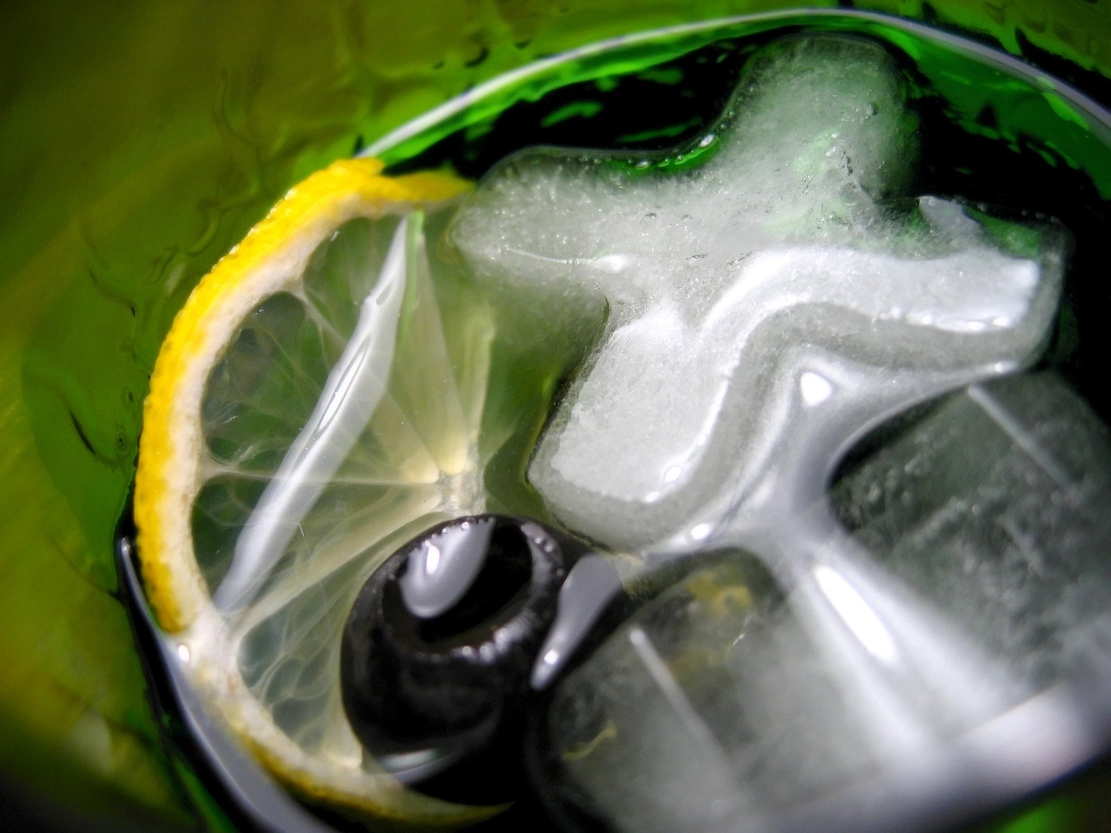 an empty green juicer with limes, ice and water
