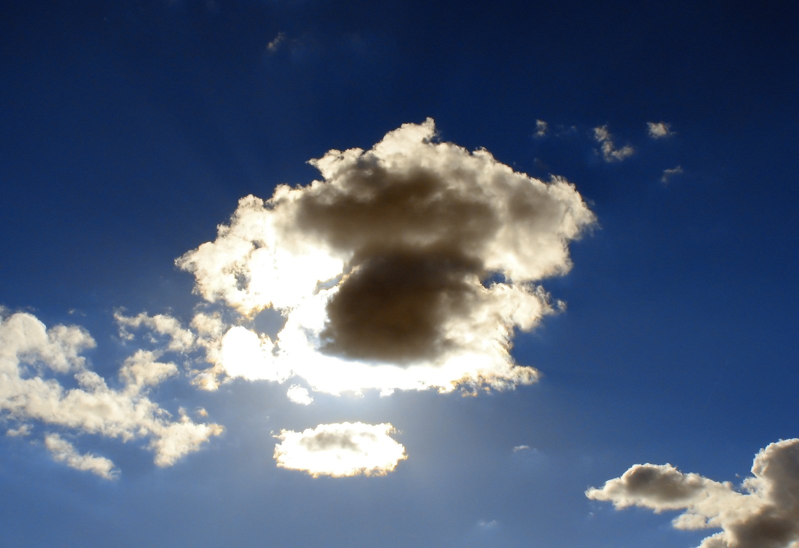 sun shining behind some clouds in the sky