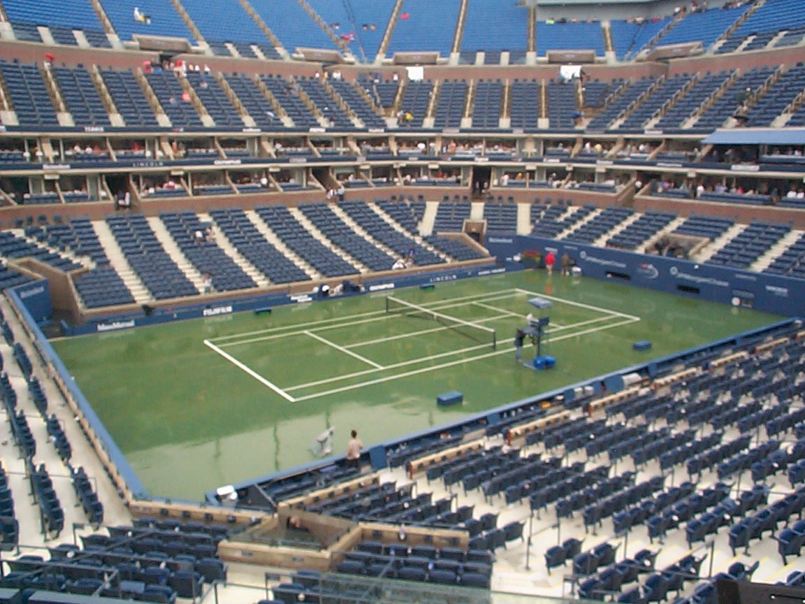people playing tennis in an empty stadium with rows of seats