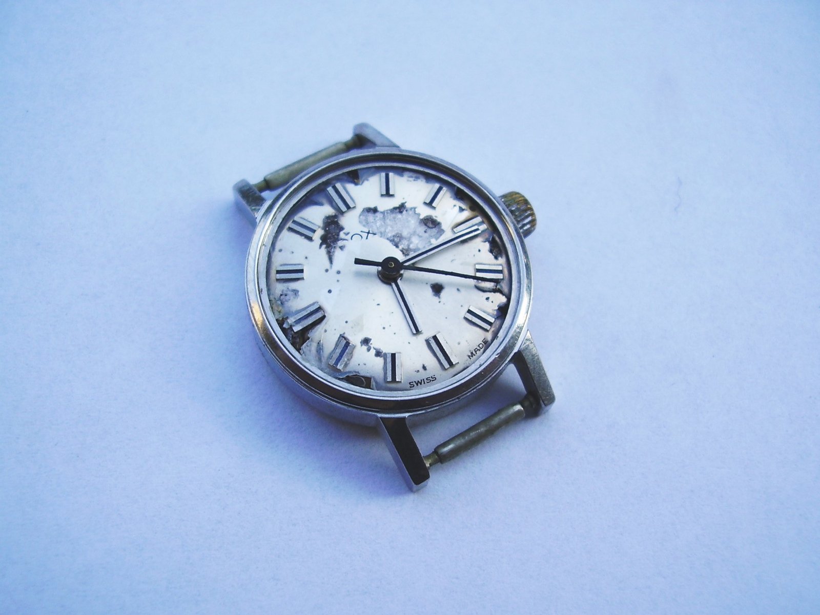 a small, white watch has it's hands extended