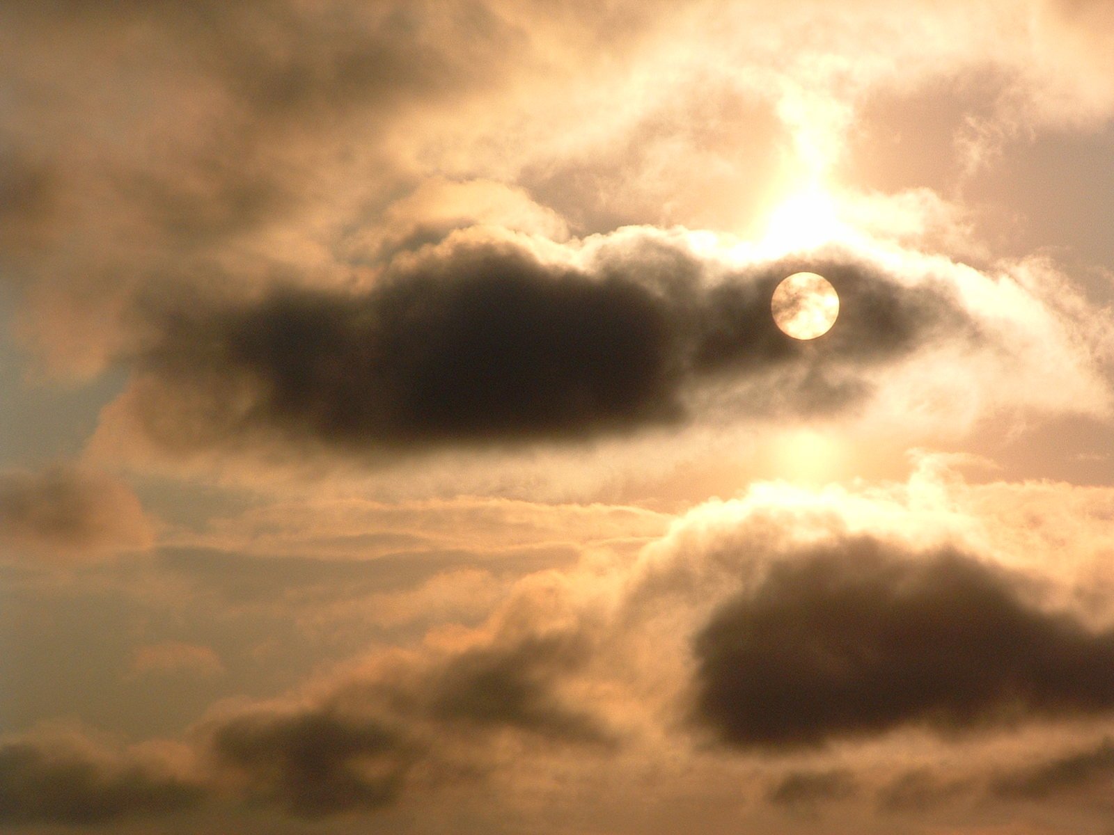 a large cloud filled sky with a full sun