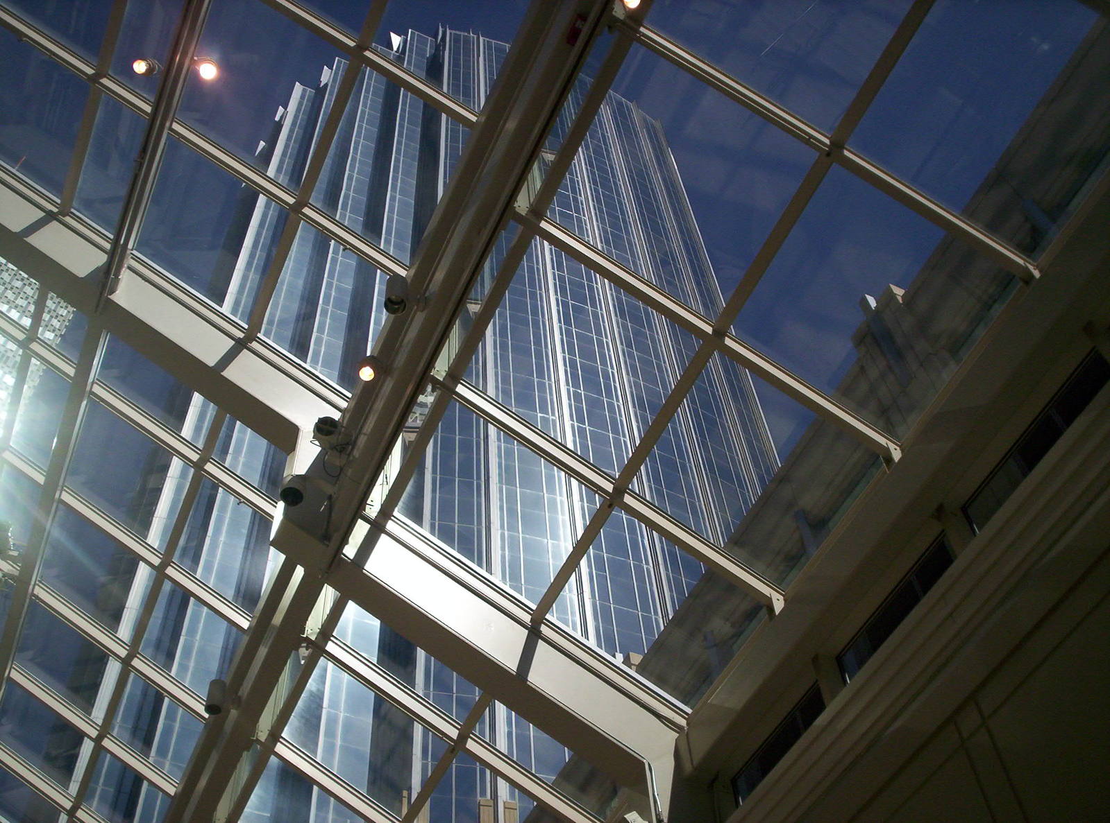 some glass windows and a building light in the distance