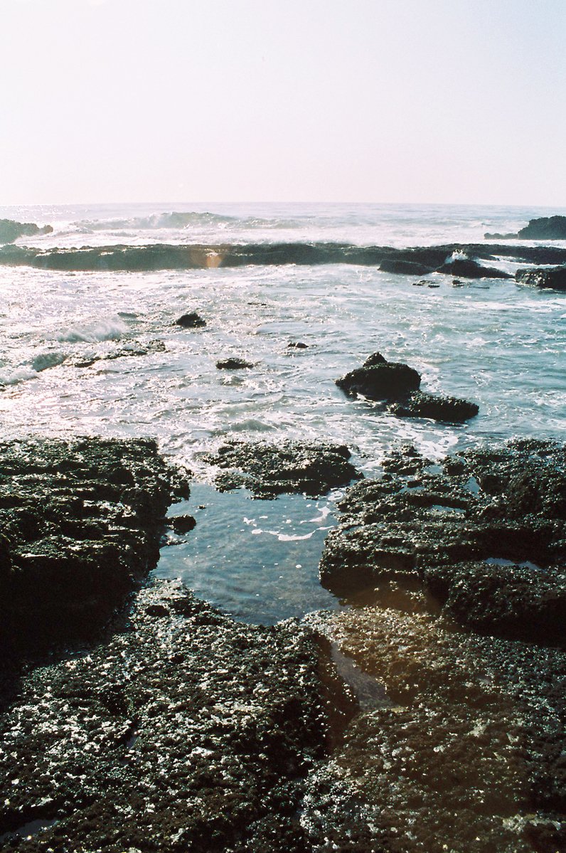 a beach covered in a body of water and surrounded by rocky shore