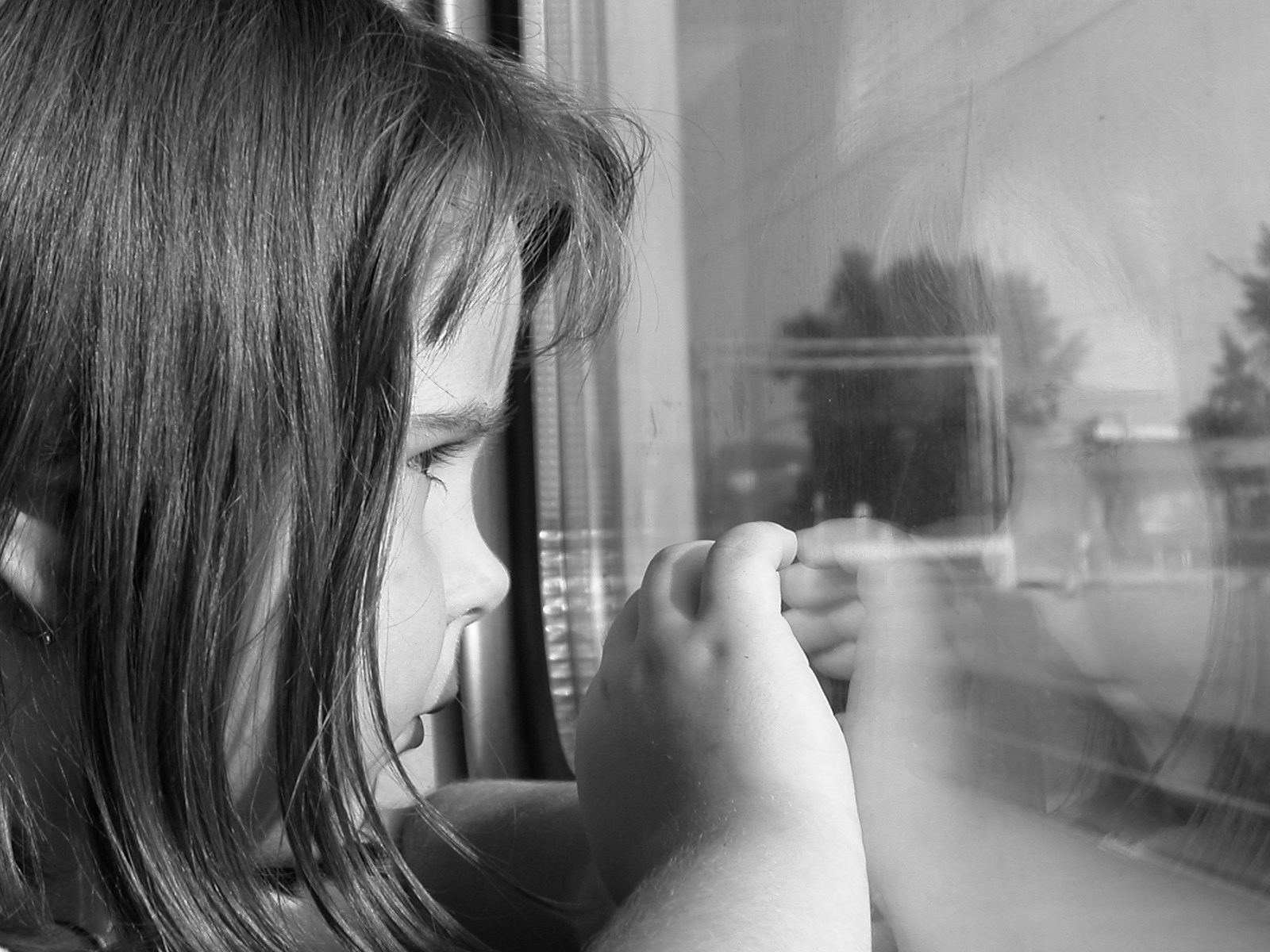 a little girl is looking at her reflection in a window