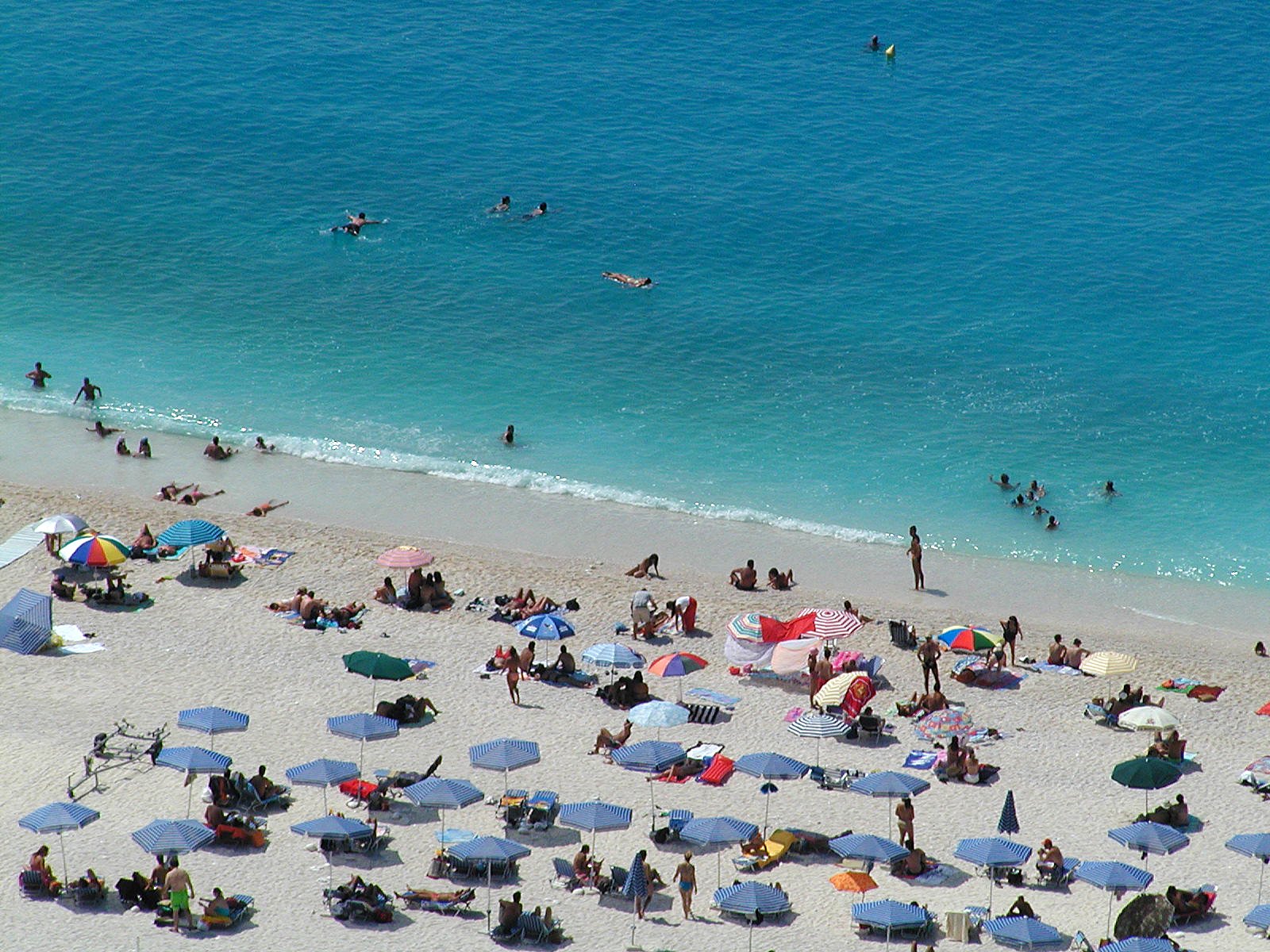 the view from above of beach umbrellas and people laying on a sandy beach