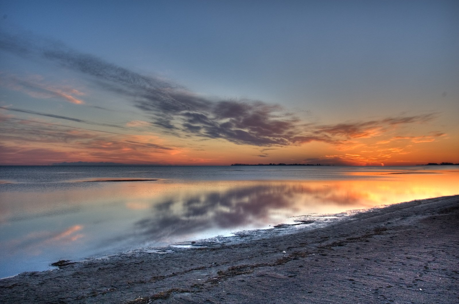 a body of water with clouds and sun reflecting on it