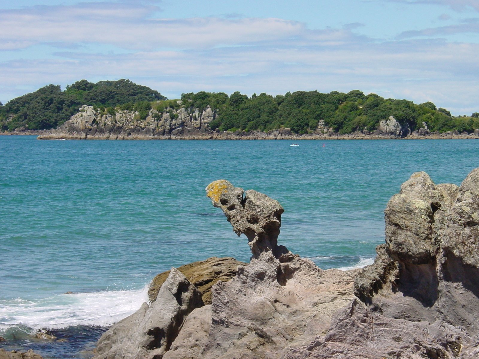 two rocks sitting on the edge of a blue lake