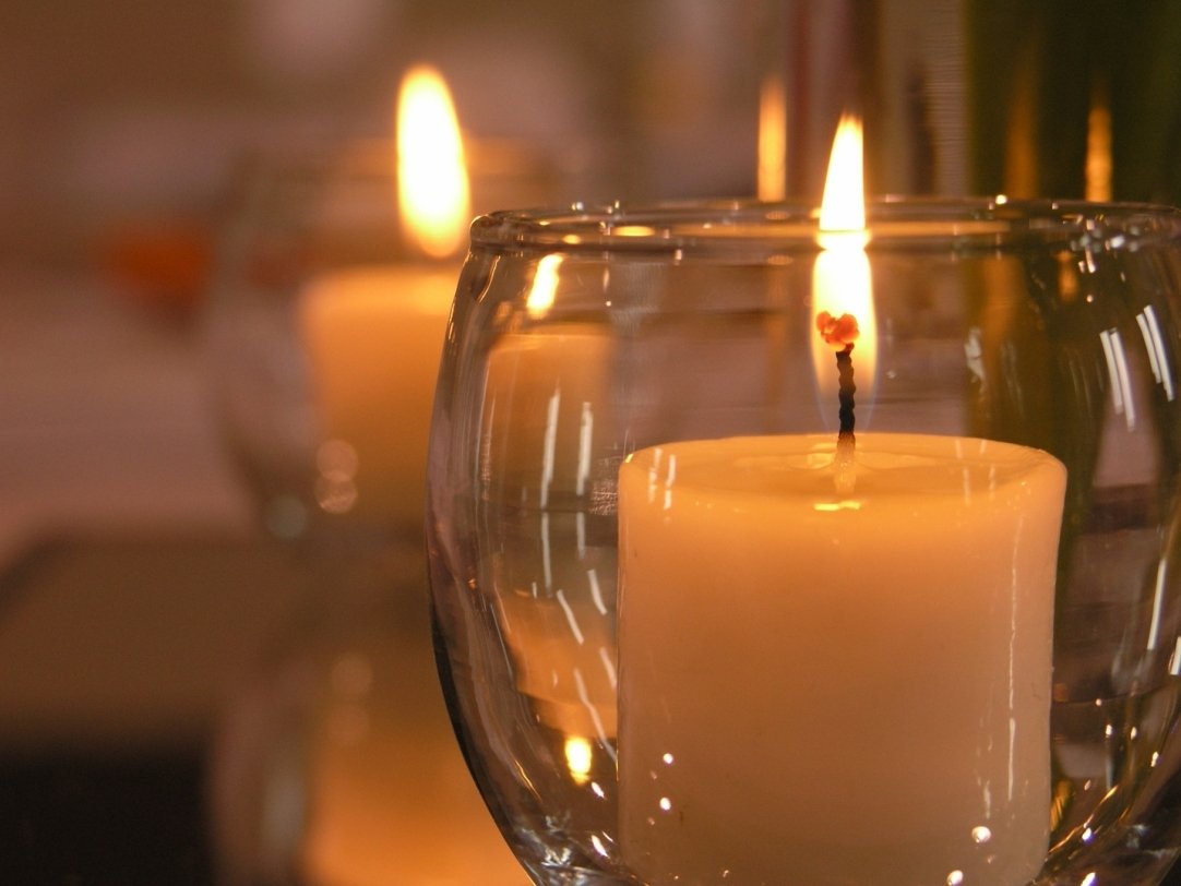 three white candles in a clear candle holder
