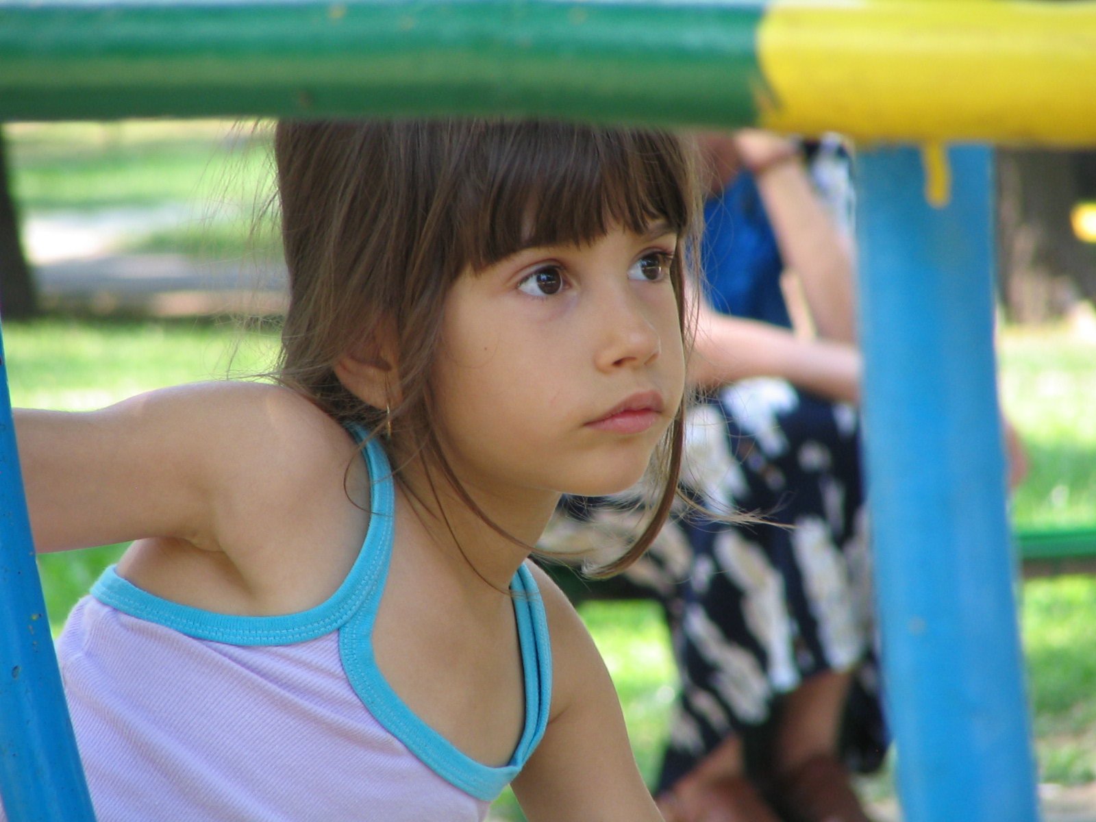 the young child in a blue and white tank top is on a swing