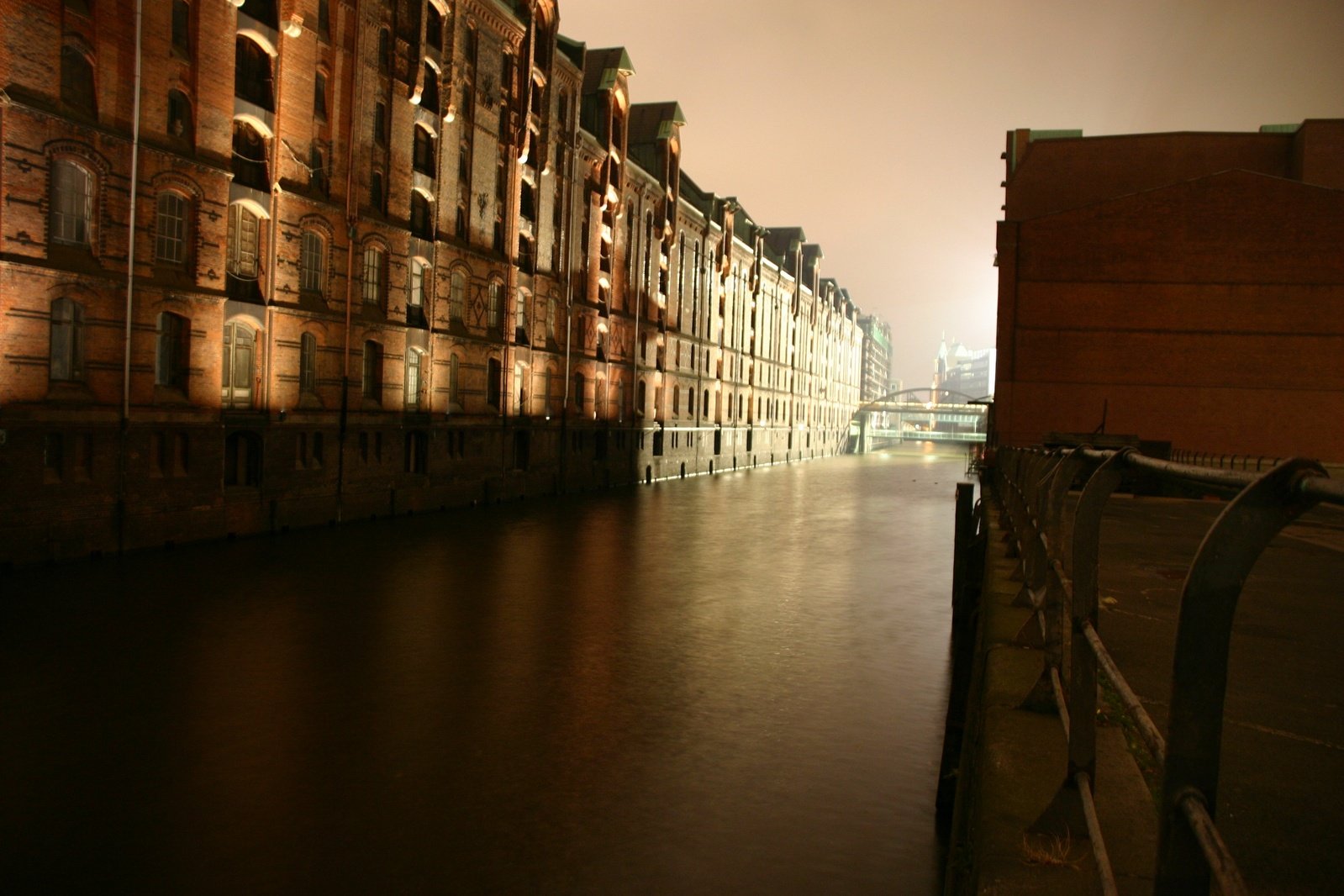 a long dark waterway running past a row of brick buildings