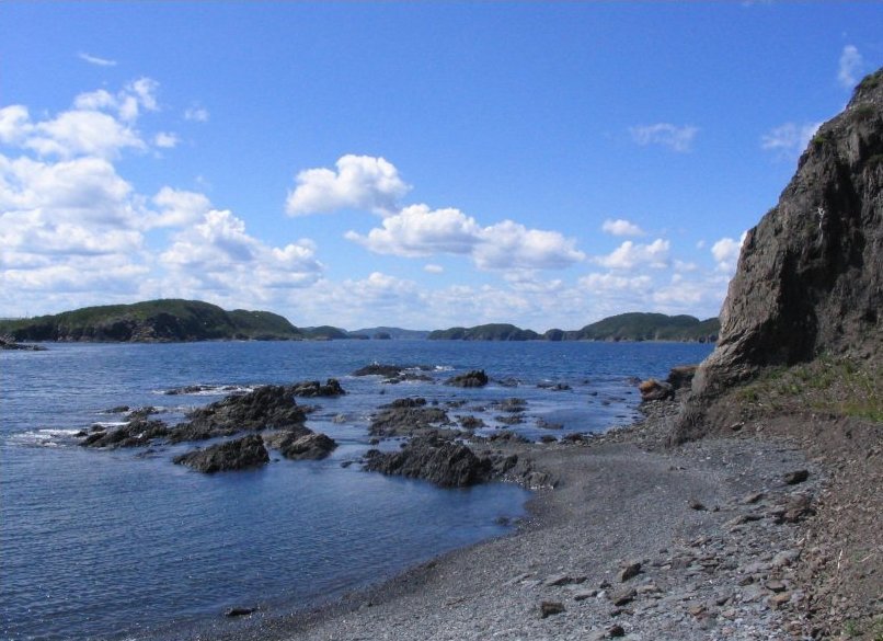 a large rock sits on the beach by water