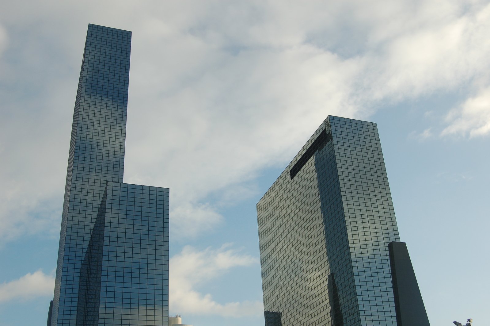 a street scene with two tall buildings against a cloudy blue sky