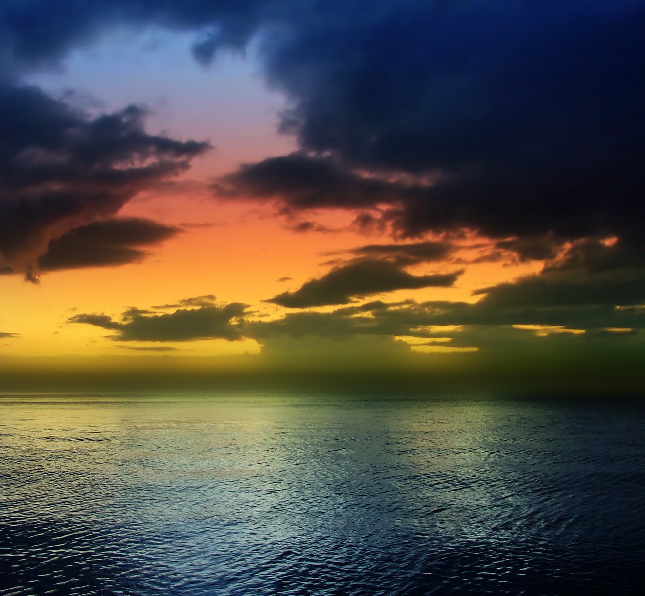 a body of water under a colorful sky with clouds