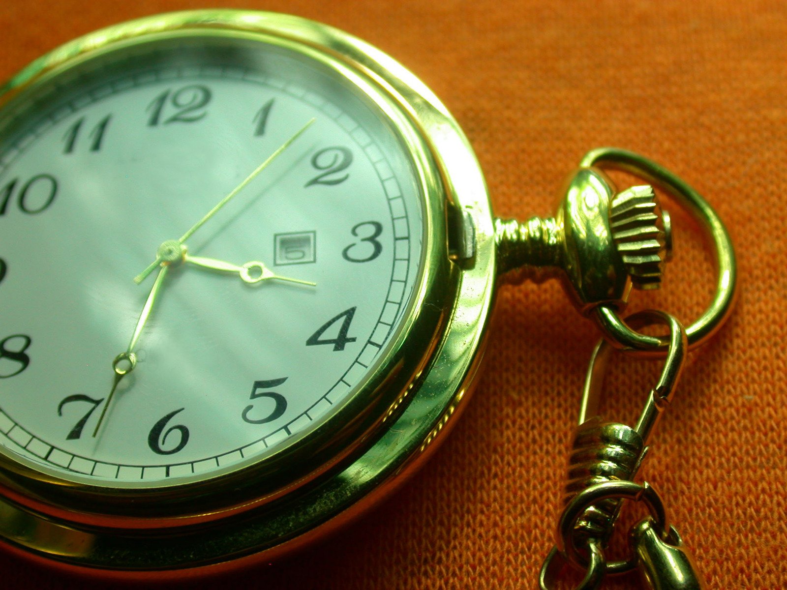a close up of an analog pocket watch with a chain
