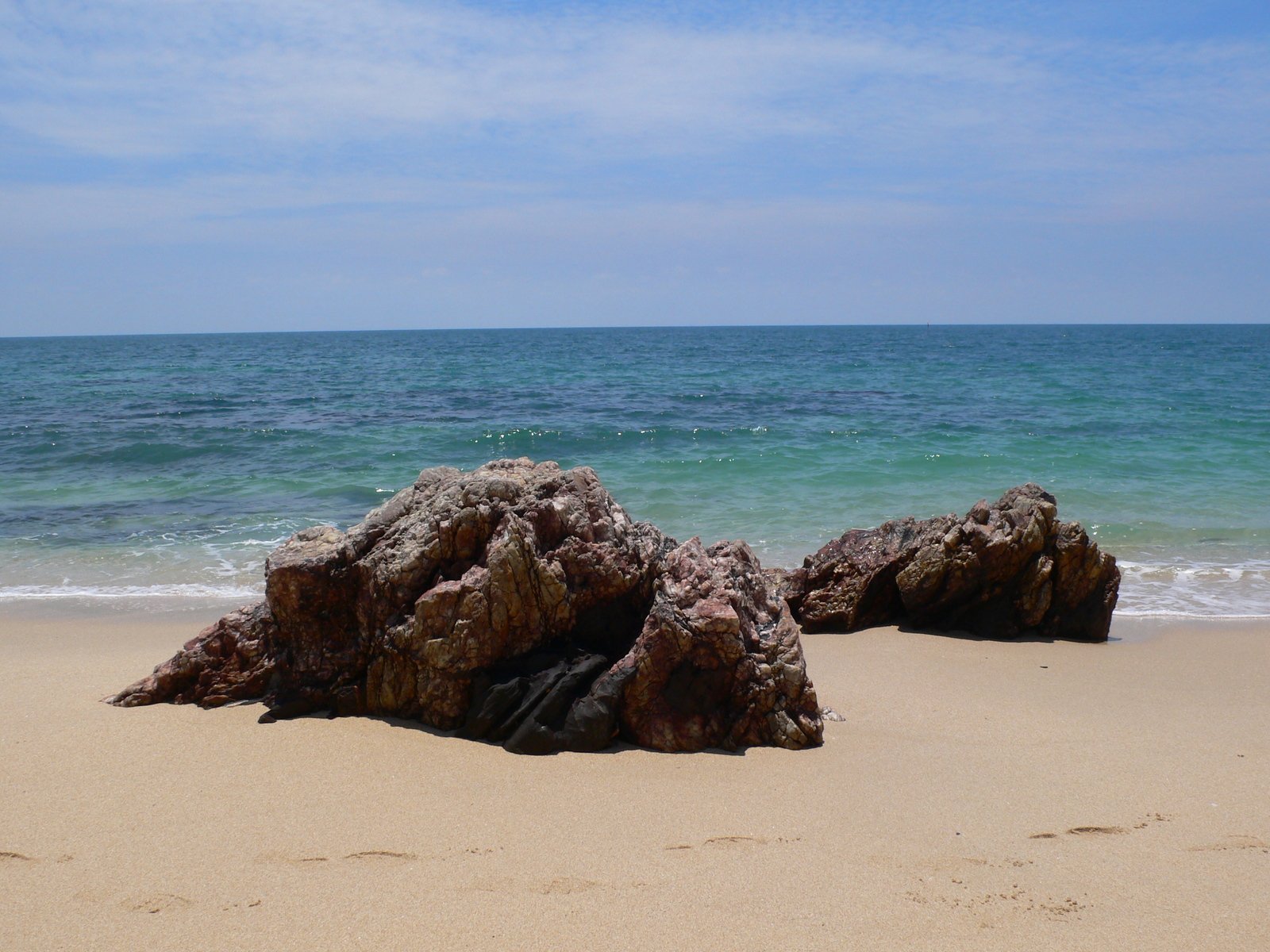 a beach with a rock formation on the shore