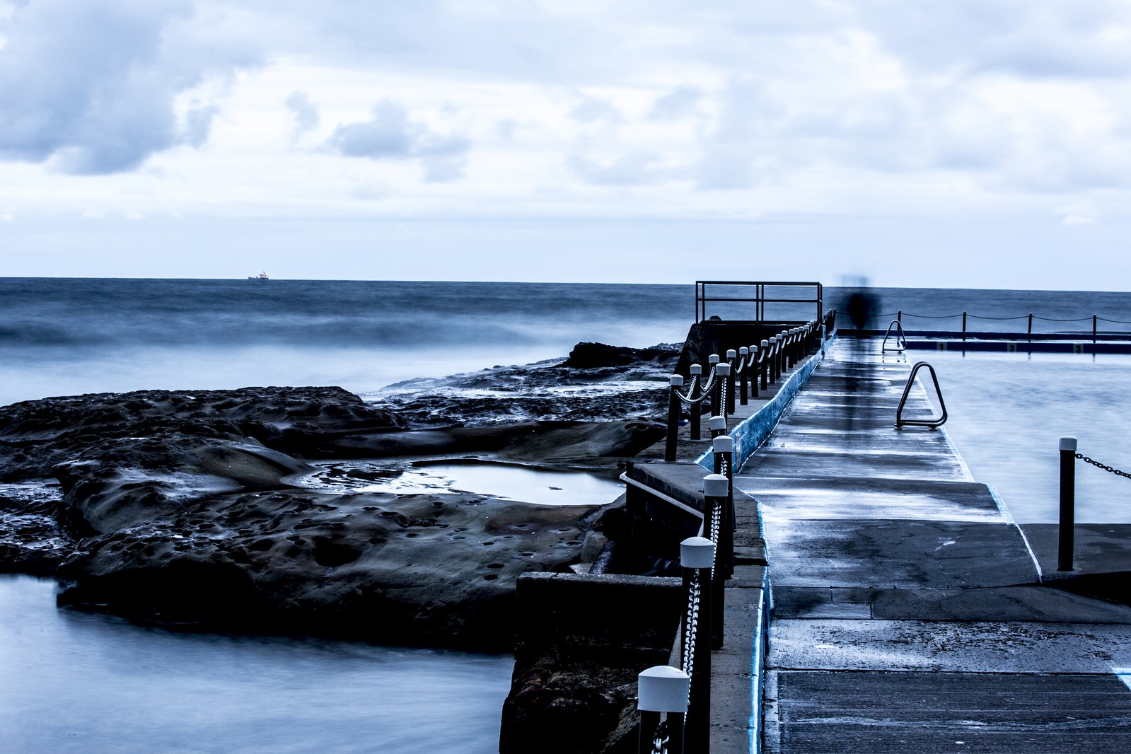 the view of the ocean from a pier in the distance