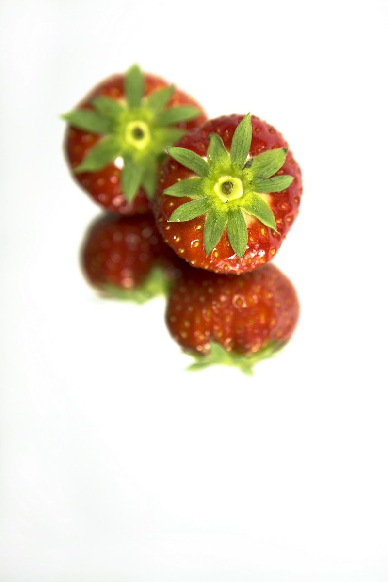 three strawberries with leaves on top of each other