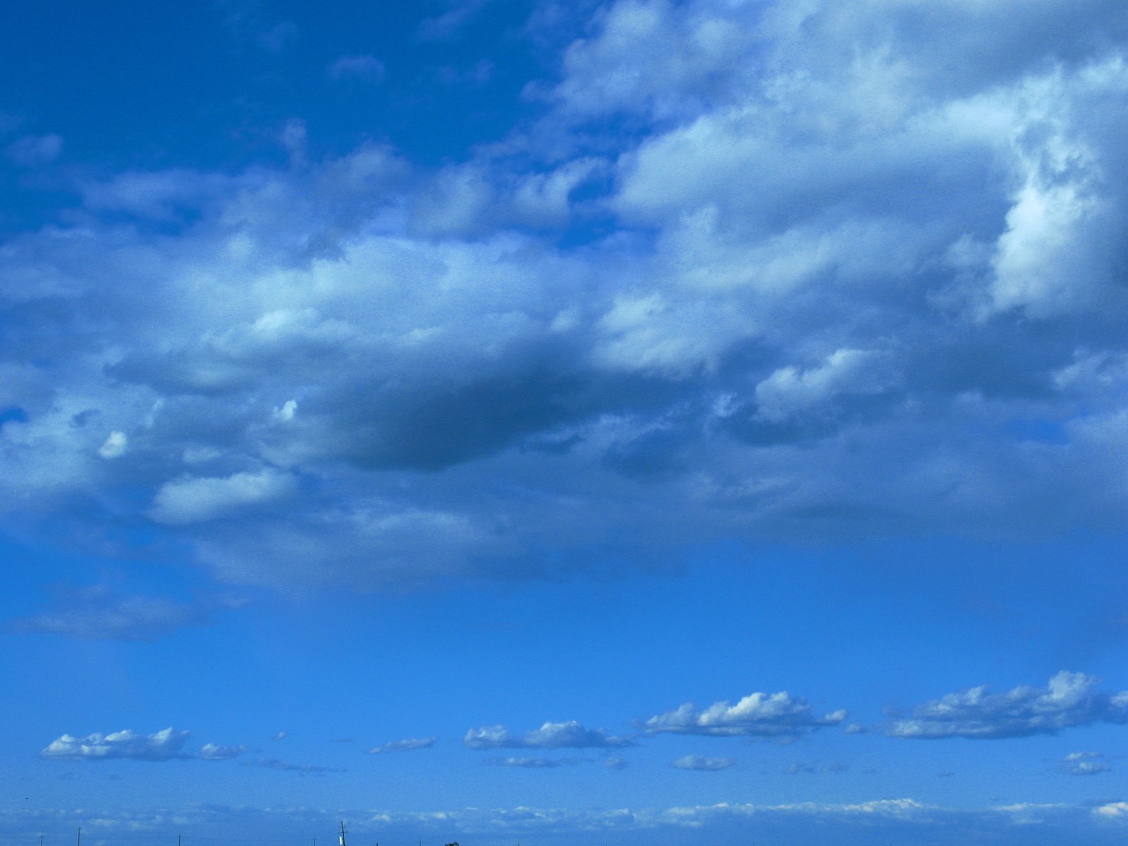 a sky filled with white clouds with blue water below