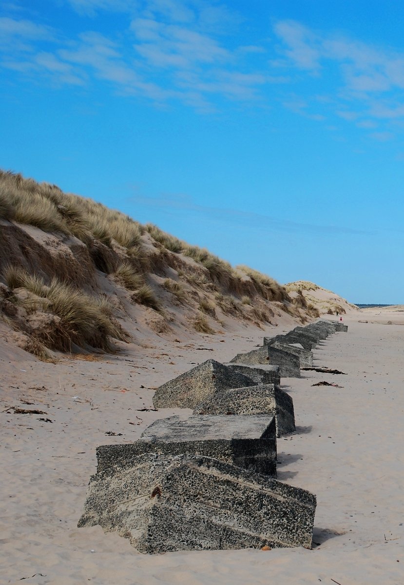 a sandy beach with benches and a blue sky