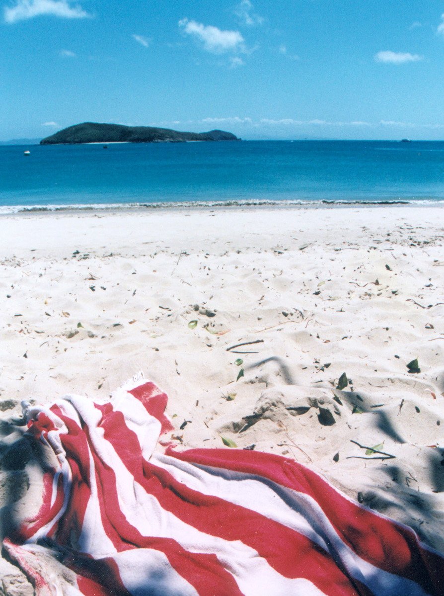 an american flag is laying on a beach towel with the island in the background