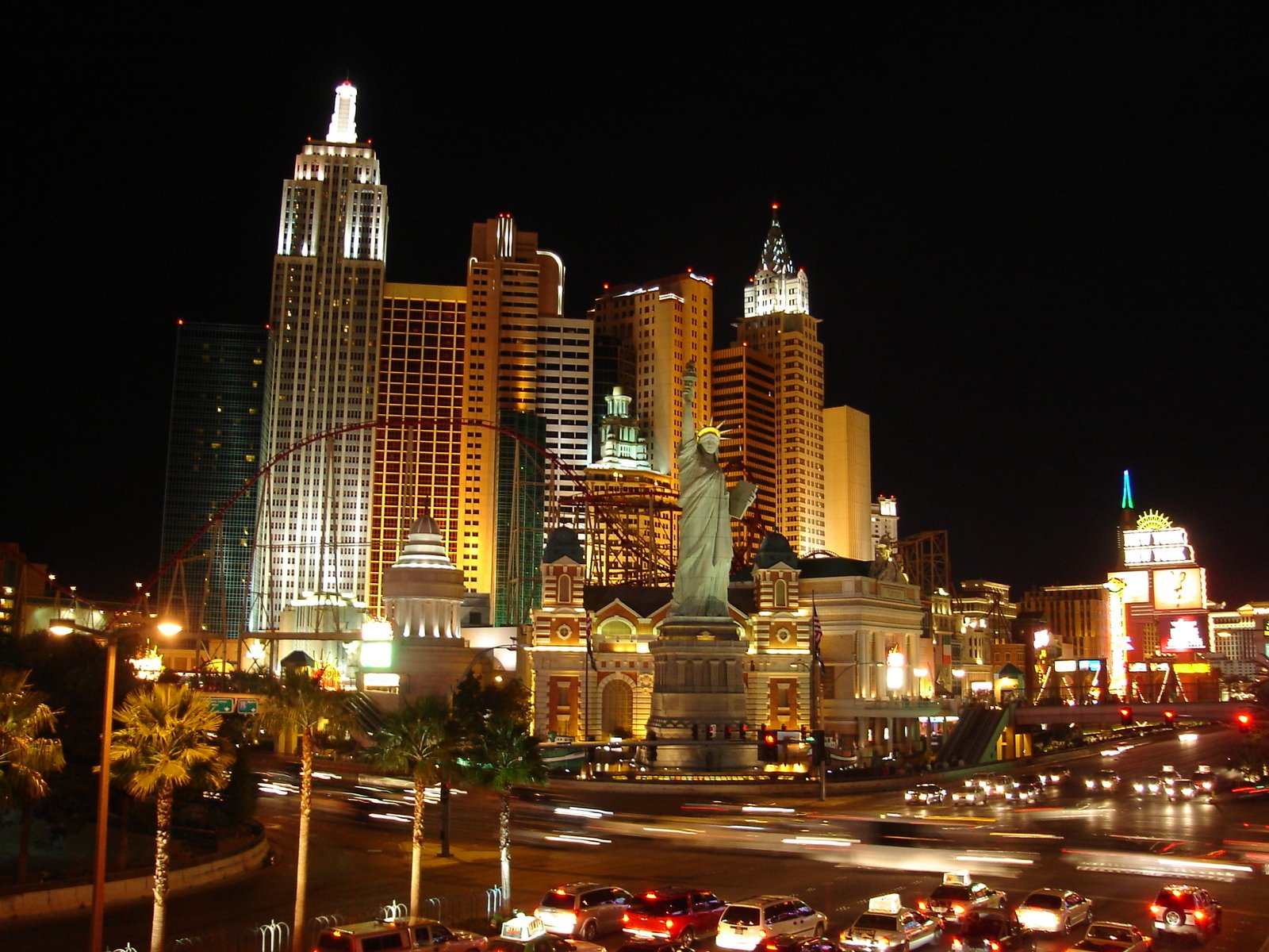 night scene of the city with a statue and traffic