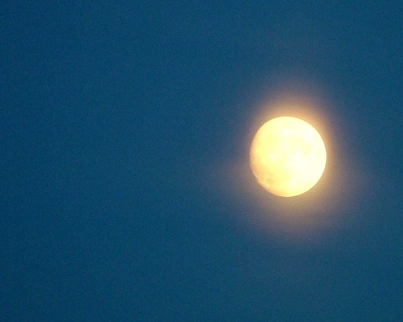 the moon, a clear, yellow glow against a blue sky