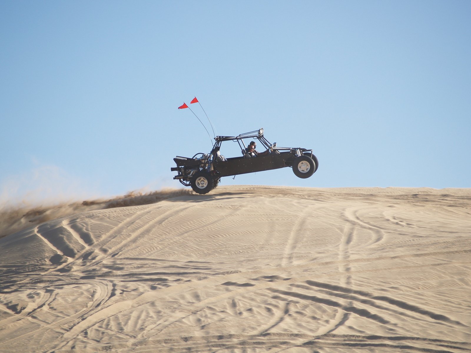 a person riding on a dune buggy flying a kite