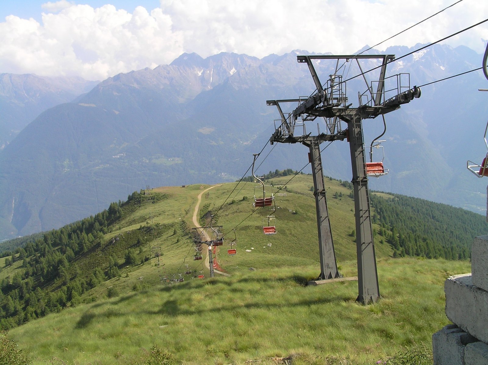 a ski lift that is on top of a green hill