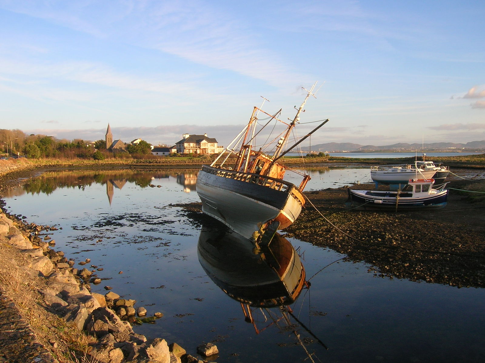 a fishing vessel docked on the shore at sunset