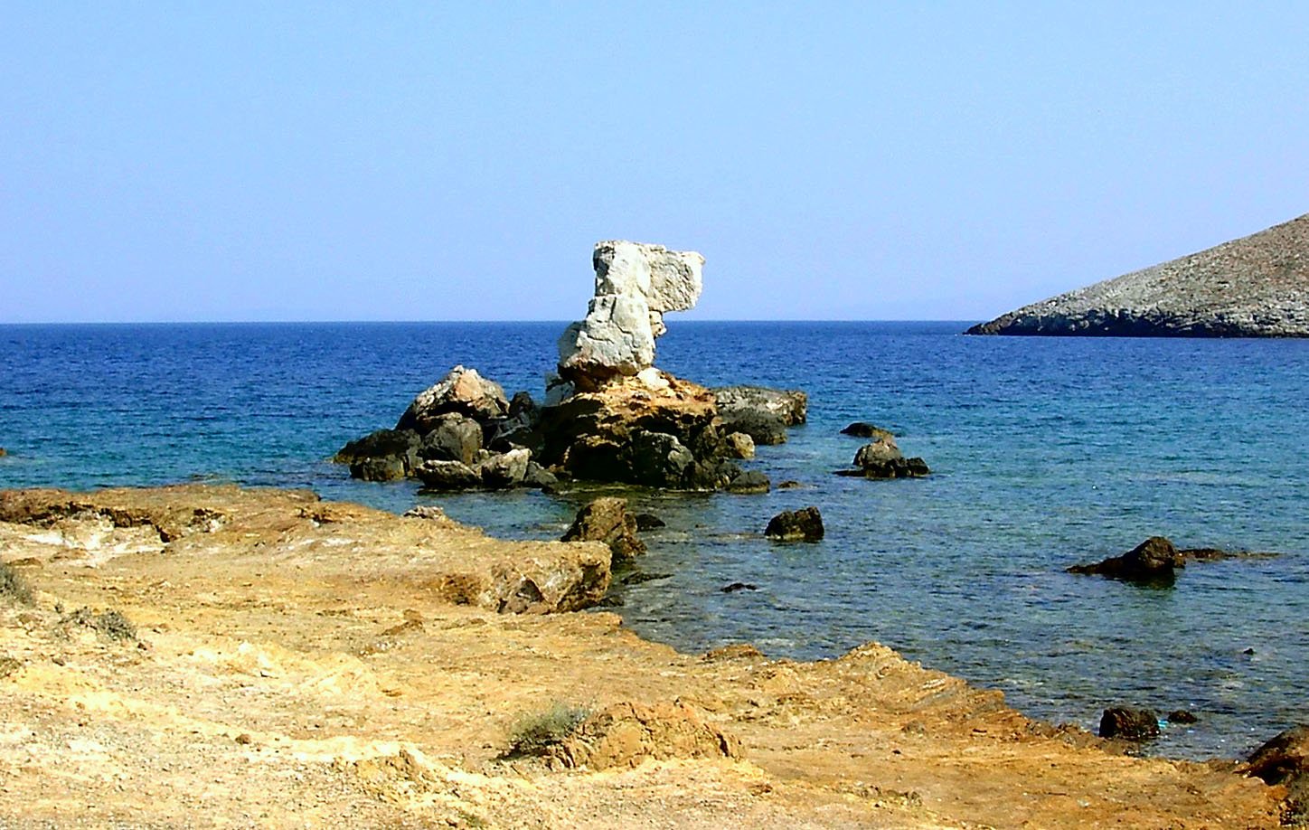 a beach area next to the ocean with a stone rock formation