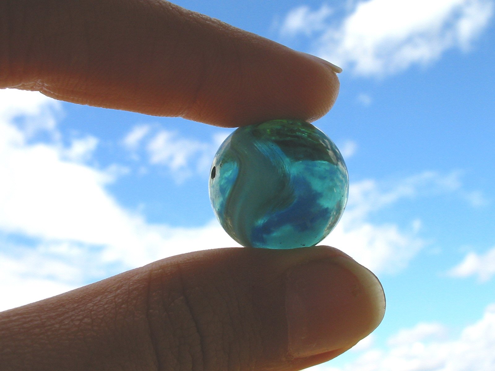 a person's hand holding a glass ball shaped object