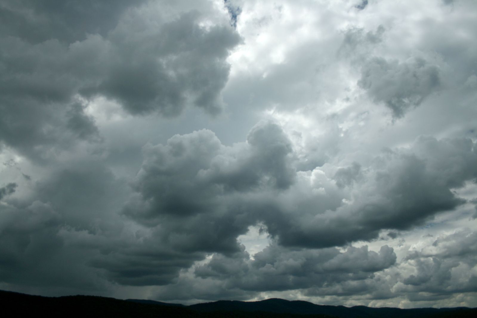 many dark clouds are hovering over a green field