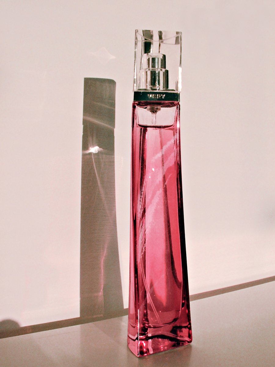 a pink perfume bottle sitting next to an empty bottle
