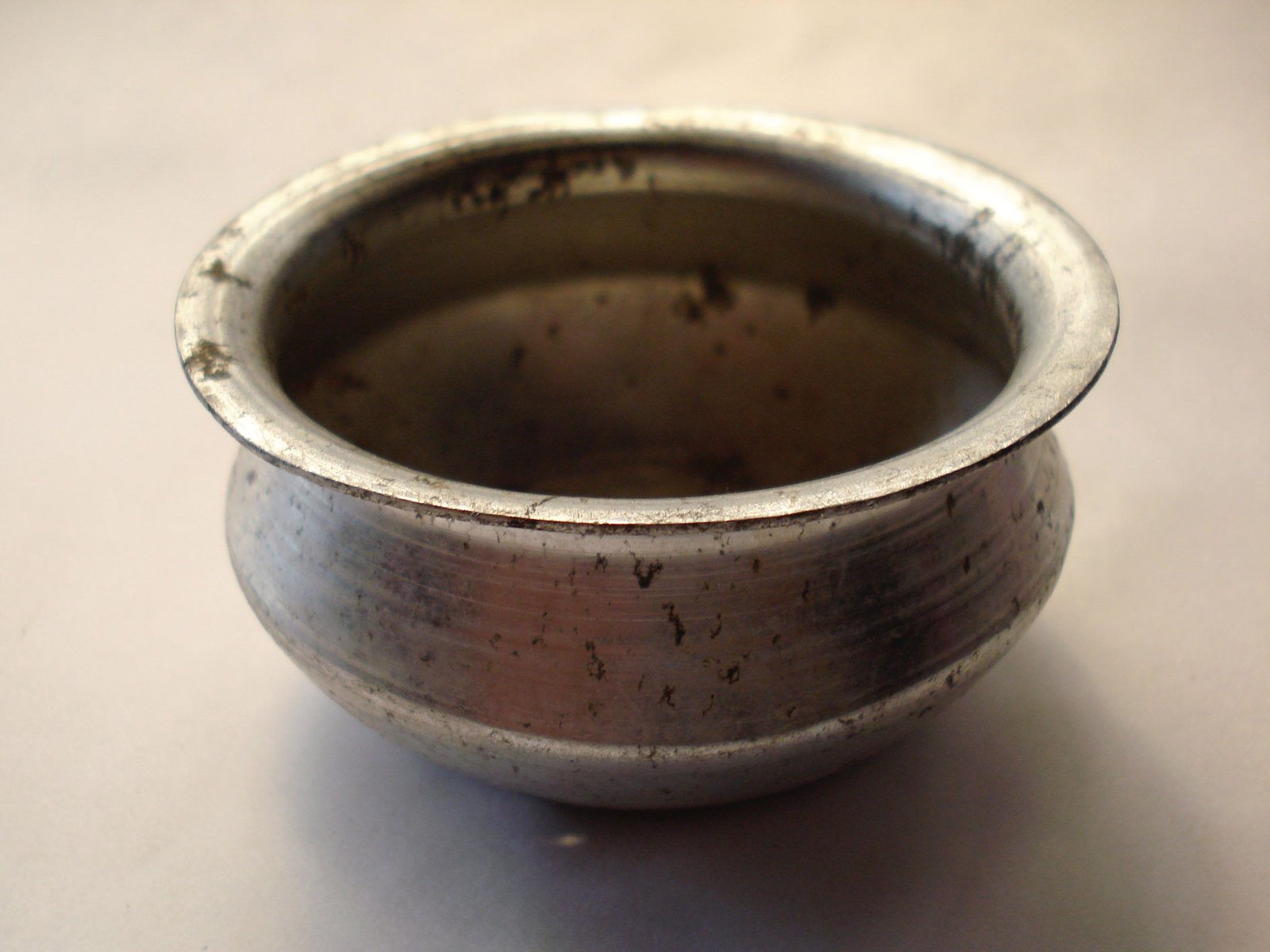 a metal bowl with a lid and an opening