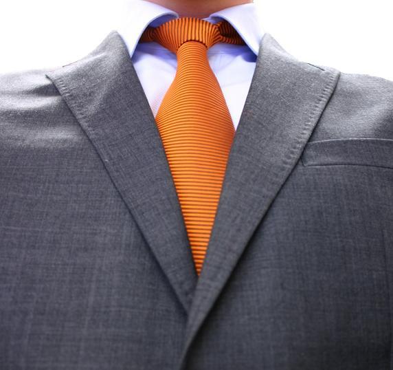 a man wearing an orange tie that is pinned to his gray suit