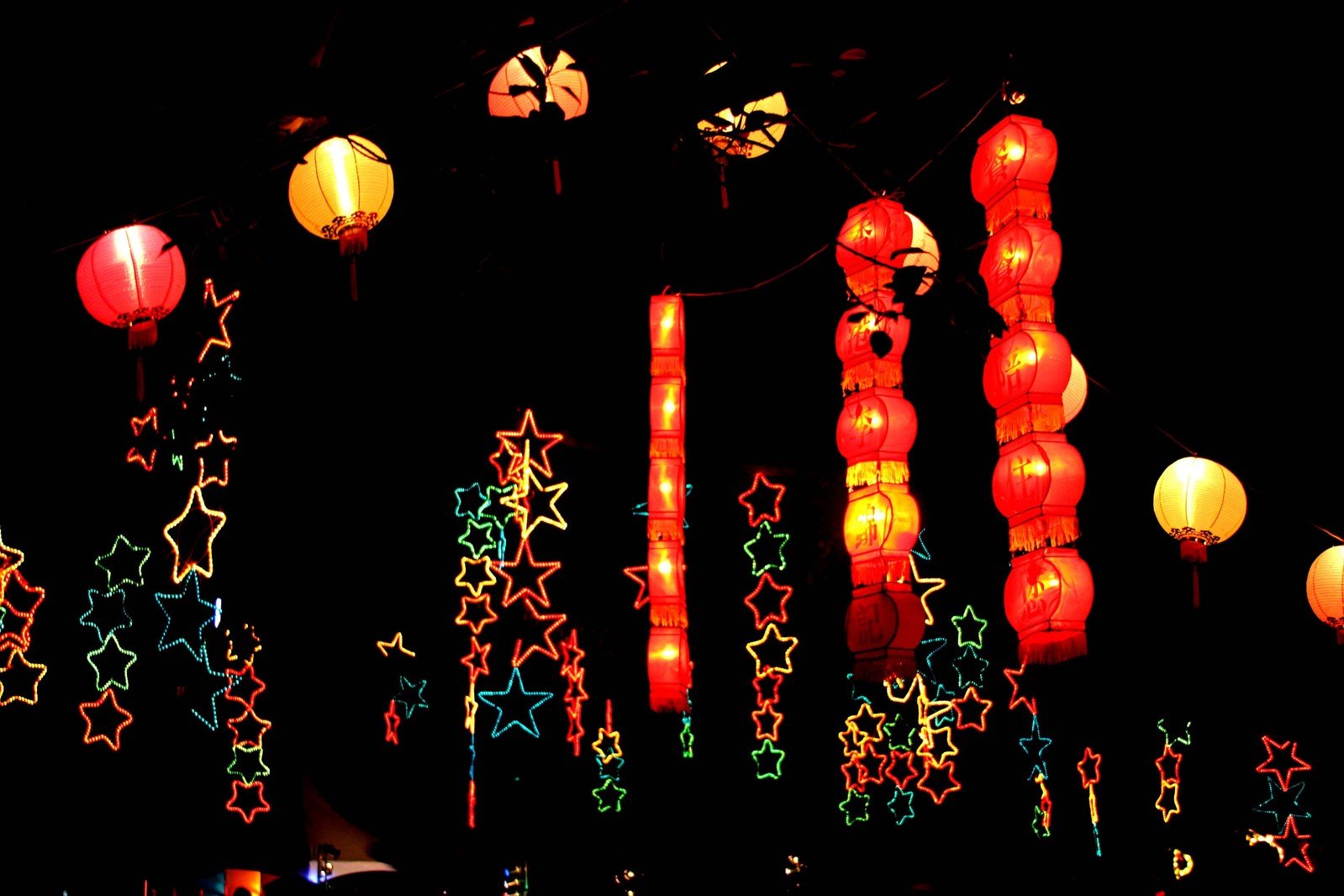 a wall of lights and paper lanterns that are red, yellow, green and white