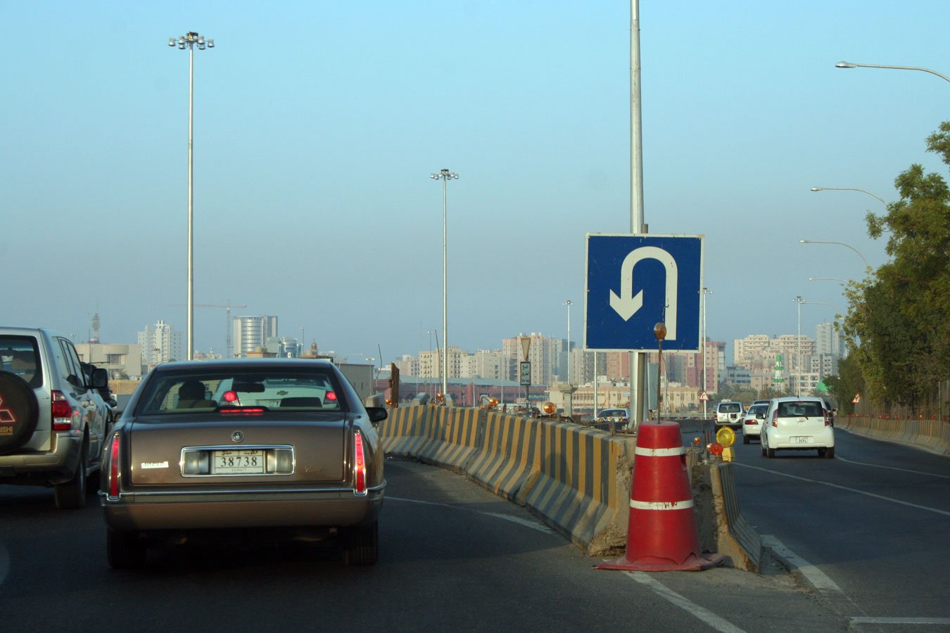 several cars drive down the busy road with signs that point in the opposite direction