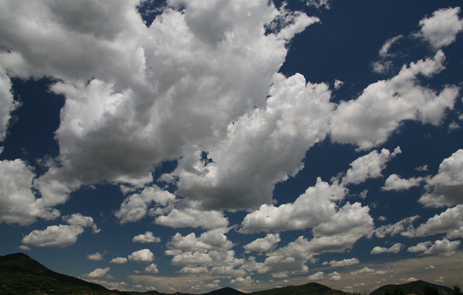 a very cloudy sky with some trees below it