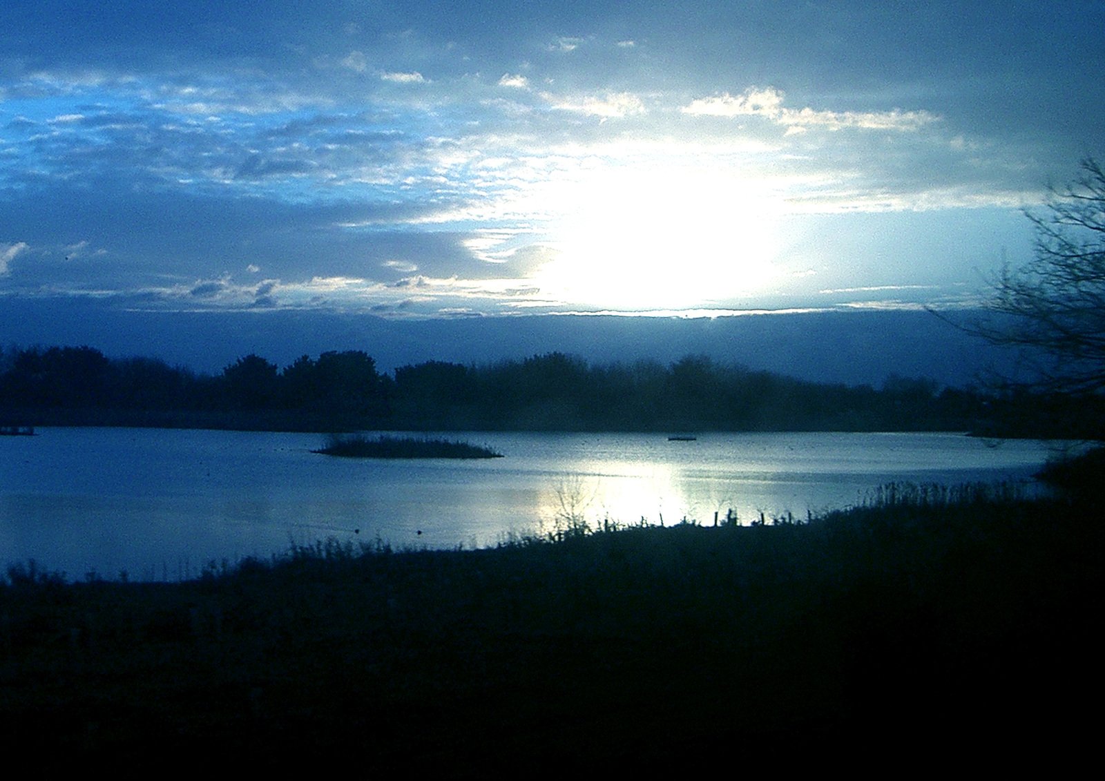 the sun shines bright on a lake at dusk