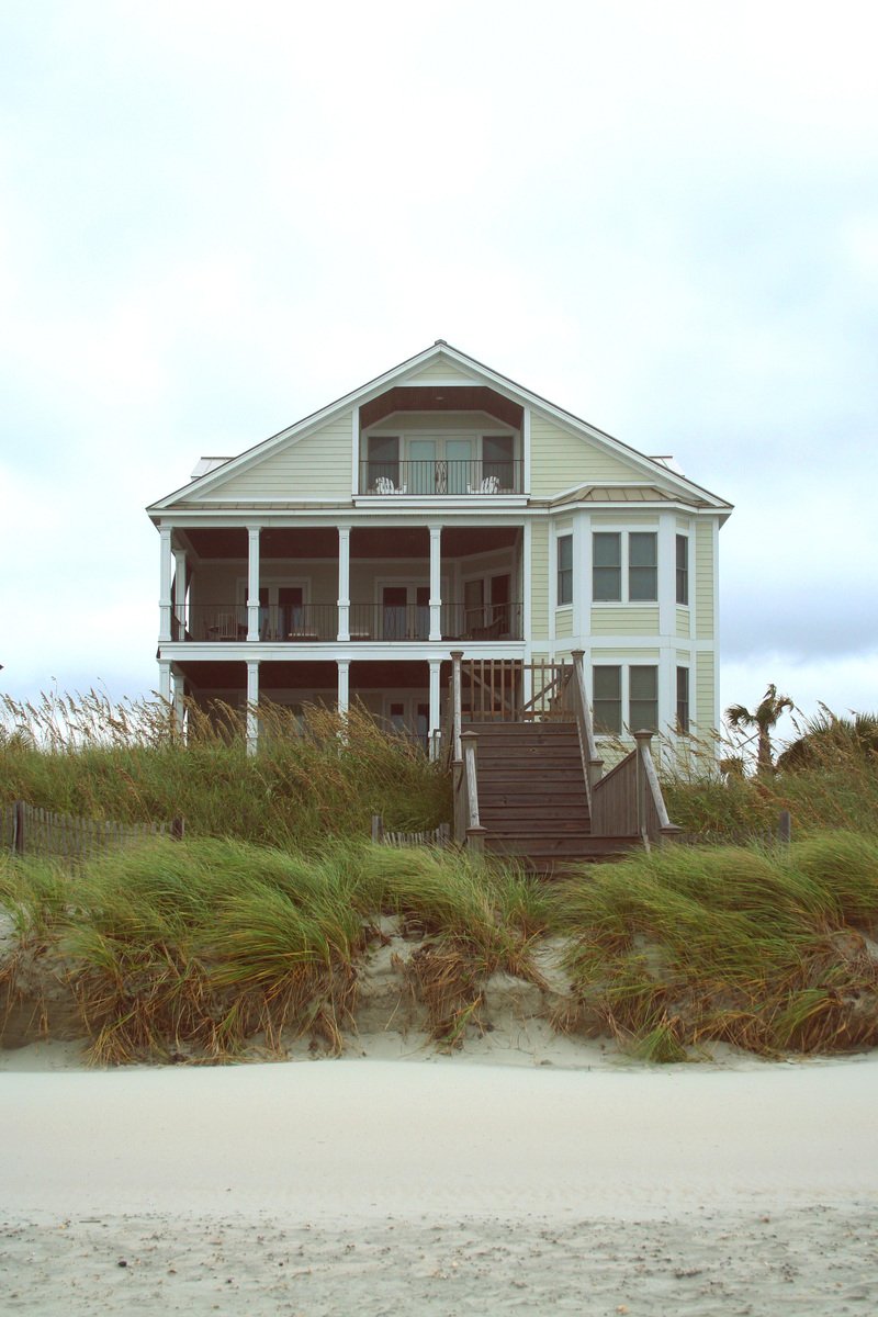 a beach house sits on the sand by the grass