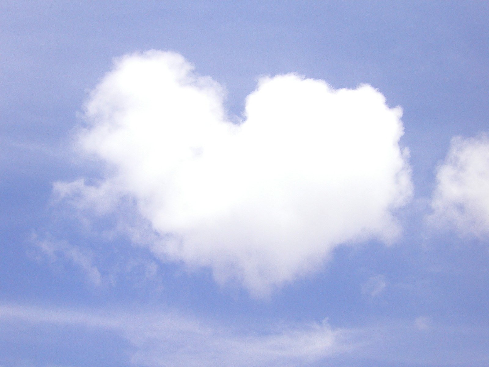 a airplane in flight with a heart shaped cloud