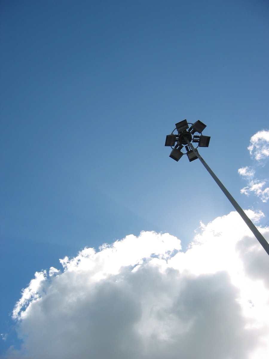 the street light on top of a pole is lit up in the blue sky