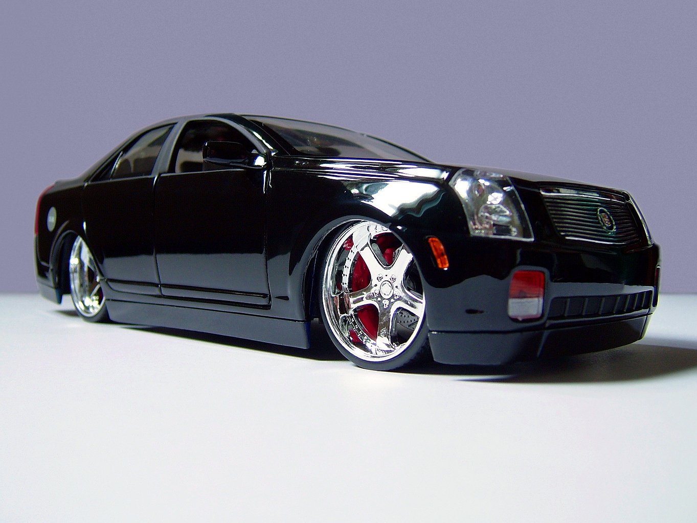 a black toy car with red tires on a white table