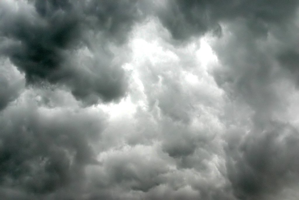 storm clouds roll in over the grass and trees